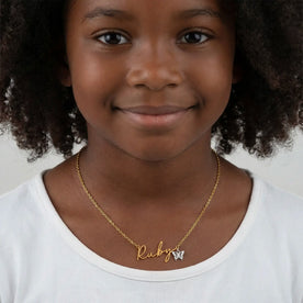 Girl wearing gold Ruby name necklace on anchor chain with silver butterfly charm - Willow font