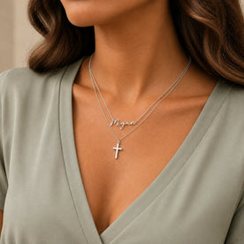 Woman wearing a platinum personalised name and cross layered necklace set - Dahlia font